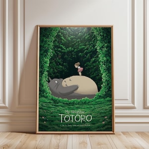 May include: Framed poster featuring the animated film "My Neighbor Totoro." The artwork depicts Totoro, a large gray forest spirit, lying on a grassy hill with a young girl standing on top. Lush green foliage surrounds them, with the film's title at the bottom.