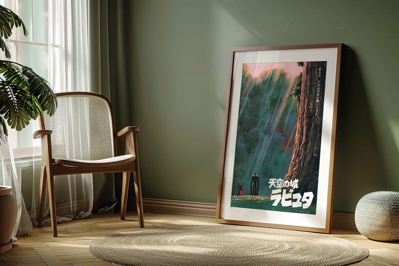May include: A framed poster featuring Japanese text and a landscape scene with figures. The poster is leaning against a green wall in a room with a wooden chair, a round rug, and a potted plant. The poster has a wooden frame.