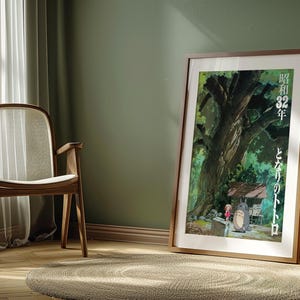 Pu&ograve; includere: Un poster incorniciato con una scena del film d'animazione "Il mio vicino Totoro". L'opera d'arte raffigura un grande albero, una piccola casa e i personaggi Totoro e Mei. Il poster &egrave; in una cornice di legno e poggia su un muro verde.