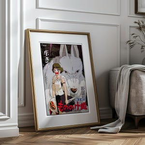 May include: Framed poster featuring anime artwork. The image shows a woman with a wolf, with Japanese text. The poster is in a gold frame and leans against a white wall and wooden floor.