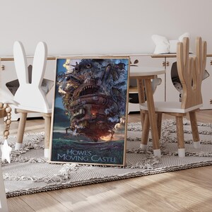 Op de afbeelding: Ingelijste poster van Howl's Moving Castle, met een gedetailleerde illustratie van het kasteel met een vurige gloed aan de basis. De poster wordt weergegeven op een vloerkleed in een kinderkamer, naast houten meubels en een kleine tafel.