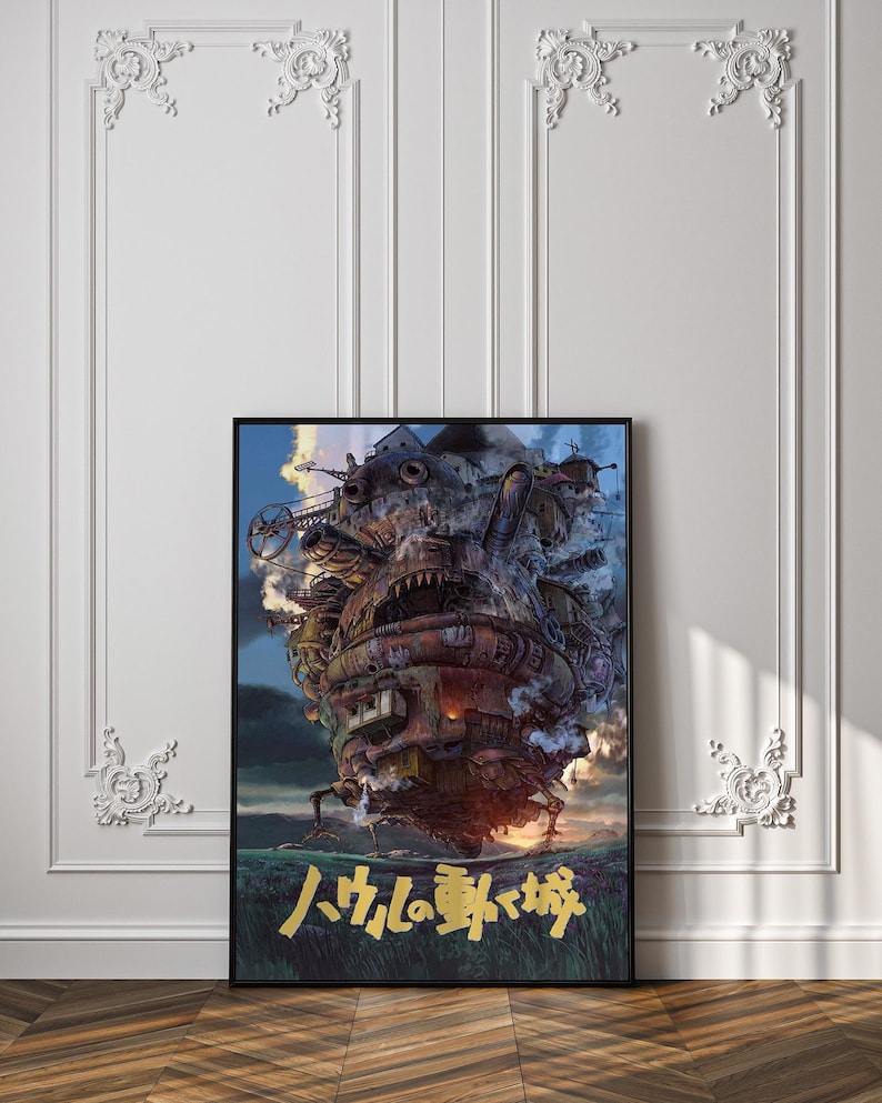 May include: Framed poster featuring a detailed illustration of a moving castle with mechanical elements, set against a cloudy sky. The castle is primarily brown and rusty, with gold Japanese text at the bottom. The poster is displayed on a white wall.