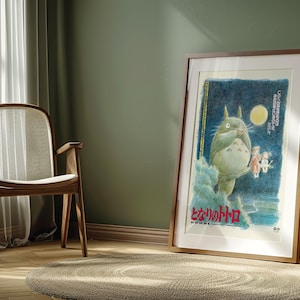 Puede incluir: Un p&oacute;ster enmarcado con una ilustraci&oacute;n caprichosa de una criatura grande, esponjosa y gris con vientre blanco, de pie frente a una luna llena. El p&oacute;ster tiene texto japon&eacute;s y se exhibe en una habitaci&oacute;n con una silla de madera y una alfombra redonda.