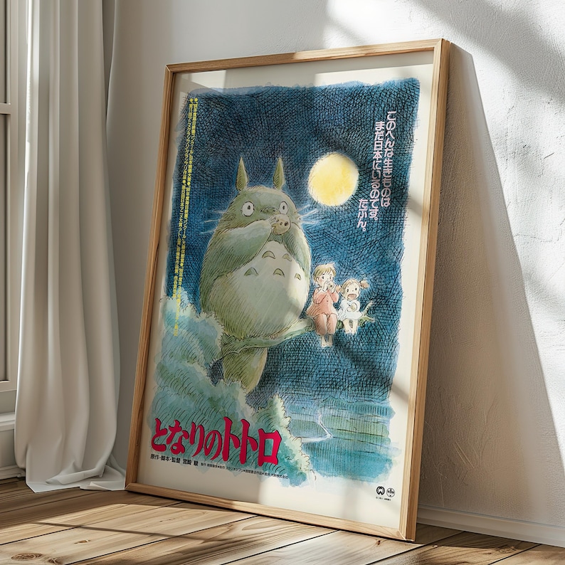 Puede incluir: Un p&oacute;ster enmarcado de la pel&iacute;cula de animaci&oacute;n "Mi vecino Totoro". La obra de arte representa al ic&oacute;nico personaje Totoro con dos ni&ntilde;os y una luna llena contra un cielo nocturno azul oscuro. Texto japon&eacute;s visible en la parte superior e inferior.