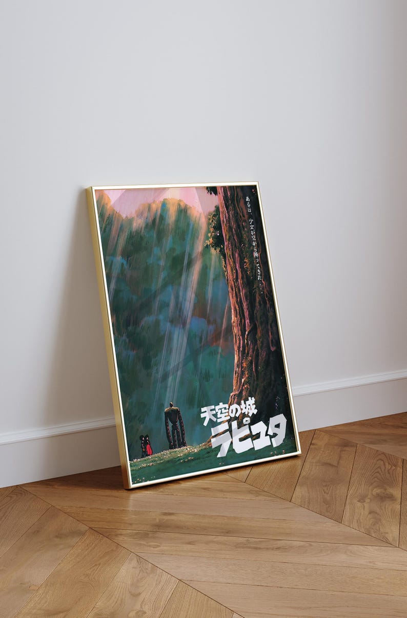 May include: Framed poster featuring artwork from the animated film "Castle in the Sky." The image depicts a towering robot, a small figure, and Japanese text against a backdrop of a forest and sky. The poster is in a gold frame.