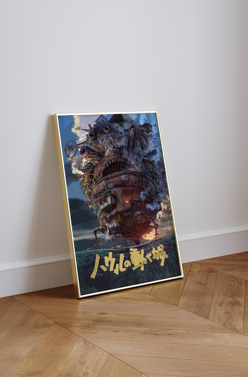 May include: Framed poster featuring a detailed illustration of a moving castle with mechanical elements, smoke, and fire. The artwork has Japanese text at the bottom and is set against a blue sky and green landscape.