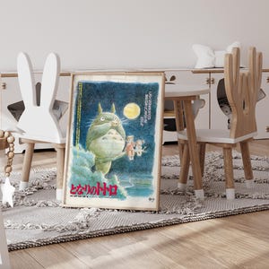 Puede incluir: P&oacute;ster enmarcado con una criatura verde y peluda sosteniendo una hoja, con una luna amarilla de fondo. Se ve texto japon&eacute;s. El p&oacute;ster est&aacute; en una habitaci&oacute;n infantil, junto a una silla blanca con forma de conejo.