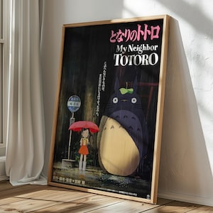 May include: A framed poster featuring the animated film "My Neighbor Totoro." The artwork depicts a young girl with a red umbrella, standing near a bus stop with Totoro, a large, friendly forest spirit, in a rainy scene. The title is in English and Japanese.