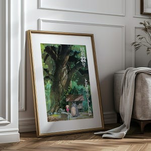 Pu&ograve; includere: Una stampa artistica incorniciata con una scena del film d'animazione "Il mio vicino Totoro". L'opera raffigura un grande albero, una bambina e Totoro vicino a un piccolo santuario. La cornice &egrave; dorata e la stampa &egrave; appoggiata a un muro.