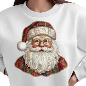 Könnte beinhalten: Weißes Sweatshirt mit einem Weihnachtsmann-Motiv. Die Santa-Illustration hat einen langen weißen Bart, runde Brille und einen roten und karierten Hut. Die Santa-Grafik ist mit Nähten und floralen Akzenten versehen, wodurch ein festliches Urlaubsdesign entsteht.
