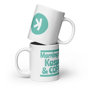 Può includere: Due tazze da caffè in ceramica bianca impilate l'una sull'altra. La tazza superiore ha un cerchio turchese con un design a freccia bianca. La tazza inferiore ha le parole "Morning Kasper & COFFEE" in turchese.