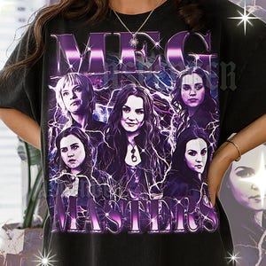 May include: Black t-shirt featuring a graphic design with the text "MEG MASTERS" in a purple, metallic font. The design includes portraits of several women with purple lightning effects.