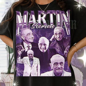 May include: Black t-shirt with a purple graphic of Martin Scorsese. The design features his name in a chrome-style font and multiple images of Scorsese in different poses, giving a vintage look.