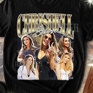 May include: Black unisex t-shirt featuring a gold-colored graphic with the text "CHRISHELL Stause" and images of the celebrity. The design includes multiple photos of the celebrity. The shirt has a crew neck.