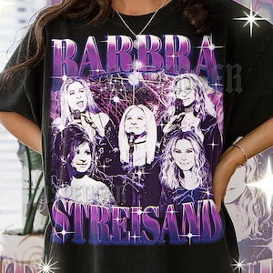 May include: Black t-shirt featuring a graphic of Barbra Streisand with a purple and blue design. The design includes the name "BARBRA STREISAND" in a retro font, and multiple images of the singer.