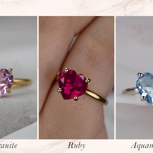 Puede incluir: Tres anillos con gemas en forma de coraz&oacute;n marcados como YOROMA. El primero es una morganita rosa en banda dorada, el segundo un rub&iacute; rojo intenso en banda dorada y el tercero una aguamarina azul claro en banda plateada, con cuatro garras.
