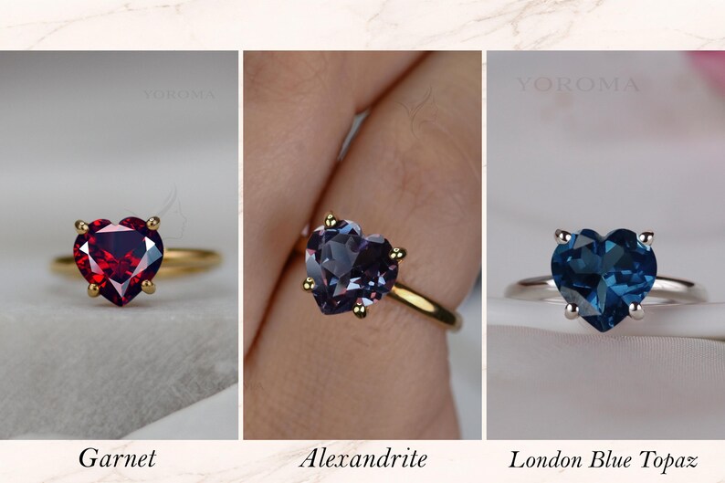 Puede incluir: Tres anillos con piedras preciosas talladas en forma de coraz&oacute;n. El primero es un granate rojo en banda dorada. El segundo es una alejandrita en banda dorada. El tercero es un topacio azul de Londres en banda plateada. Cada uno dice YOROMA.