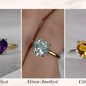 Puede incluir: Tres anillos con piedras preciosas en forma de coraz&oacute;n. El primero es una amatista morada en banda dorada, el segundo una amatista verde claro en banda dorada y el tercero un citrino amarillo en banda plateada. Cada anillo tiene cuatro garras.
