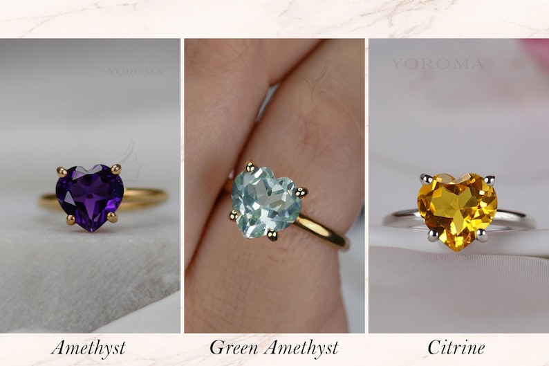 Puede incluir: Tres anillos con piedras preciosas en forma de coraz&oacute;n. El primero es una amatista morada en banda dorada, el segundo una amatista verde claro en banda dorada y el tercero un citrino amarillo en banda plateada. Cada anillo tiene cuatro garras.
