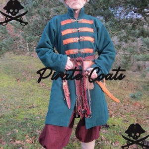 Op de afbeelding: Een teal jas met oranje details en decoratieve knopen. De jas wordt gecombineerd met een bordeauxrode broek en een bruine riem met een mes en zwaard. De tekst "Pirate Coats" is zichtbaar.