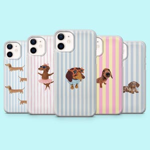 Op de afbeelding: Vijf telefoonhoesjes met teckelontwerpen. De hoesjes hebben verticale strepen in pastelkleuren van blauw, roze en geel. Elke hoes toont een andere teckelillustratie, sommige dragen accessoires zoals zonnebrillen en tutu's.