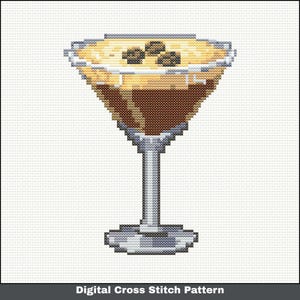 May include: A digital cross stitch pattern of a cocktail in a martini glass. The drink is a mix of brown and tan, with three coffee beans on top. The glass has a silver stem and base, and the background is white.