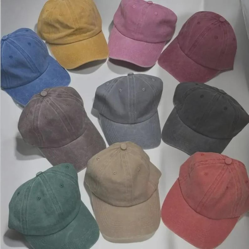 Puede incluir: Una colecci&oacute;n de diez gorras de b&eacute;isbol en varios colores, incluyendo azul, amarillo, rosa, burdeos, gris, marr&oacute;n, verde, beige y rojo. Cada gorra tiene una visera curva y un bot&oacute;n superior.