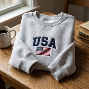 May include: A white ceramic mug with a black handle and the text "But First, Coffee" in a black, handwritten-style font. The mug is on a white surface.