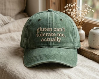 May include: A green baseball cap with the embroidered text "gluten can't tolerate me, actually". The cap has a curved peak and a classic six-panel design. The hat is made of a soft, worn material.