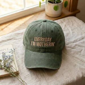 Peut inclure: Casquette de baseball vert olive avec le texte brod&eacute; "EVERYDAY I'M MOTHERIN'". La casquette a une visi&egrave;re incurv&eacute;e et une conception classique &agrave; six panneaux. Le chapeau est fait d'un mat&eacute;riau doux et us&eacute;.