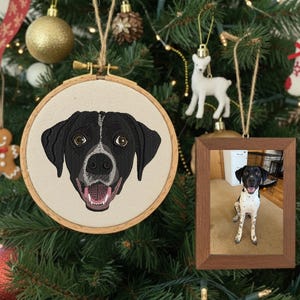 以下が含まれることがあります： クリスマスツリーには、額入りの写真や刺繍された犬の肖像画など、オーナメントが飾られています。犬の肖像画は、口を開けた白黒の犬です。額入りの写真は同じ犬です。その他のオーナメントには、金のボールと白い鹿が含まれています。