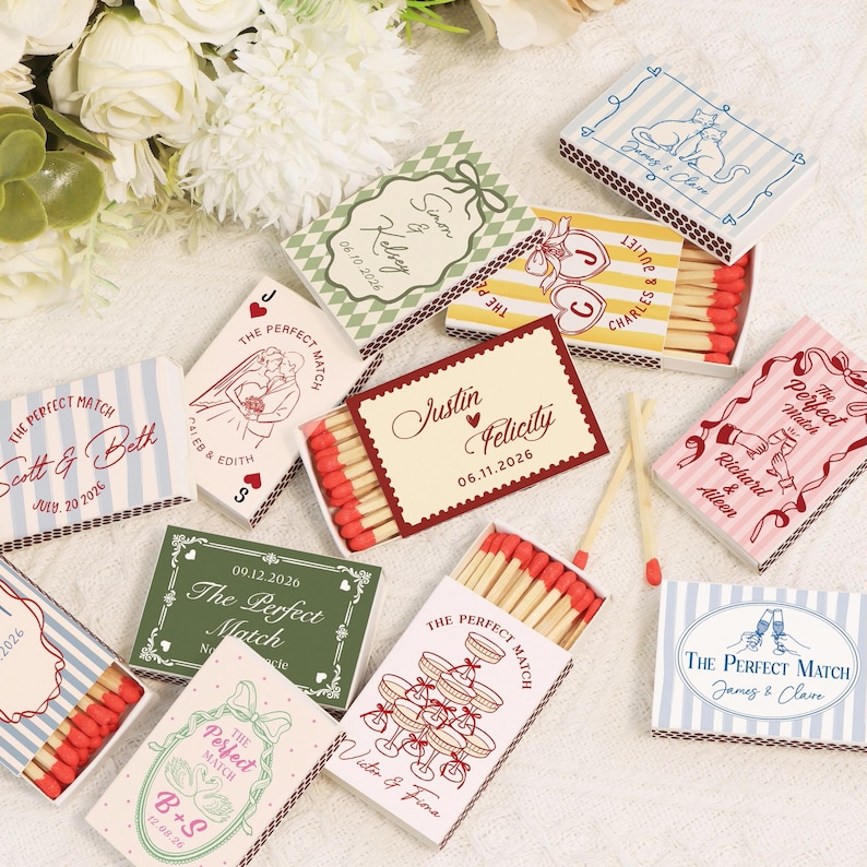 Op de afbeelding: Een verzameling decoratieve lucifersdoosjes met diverse ontwerpen en teksten, waaronder namen en data. De doosjes tonen verschillende kleurenschema's en illustraties, perfect voor huwelijksbedankjes of speciale evenementen.