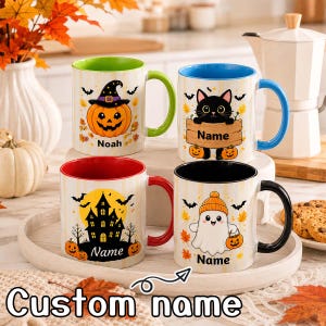 May include: Four ceramic mugs with Halloween-themed illustrations. One features a pumpkin with a witch hat and the name Noah, one a black cat with a wooden sign, one a haunted house, and one a ghost holding a pumpkin, all with custom name spaces.