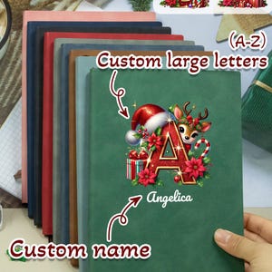 May include: A stack of personalized notebooks in various colors, with the text "Custom large letters" and "Custom name". The front notebook is green with a Christmas-themed letter "A" design and the name "Angelica".