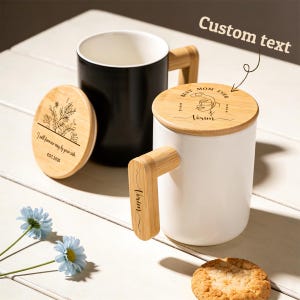 May include: Two ceramic mugs with bamboo handles and lids. One mug is black, the other white. The white mug has a lid with the text "BEST MOM EVER" and "Vorim". The black mug has a lid with the text "I will forever stay by your side" and "EST.2026".