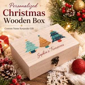 Könnte beinhalten: Eine rechteckige, helle Holzschatulle mit Metallverschluss, die auf dem Deckel ein aufgedrucktes Design aus drei stilisierten Weihnachtsbäumen und den Schriftzug "Sophia's Treasures" zeigt. Die Box ist mit festlicher Dekoration abgebildet.