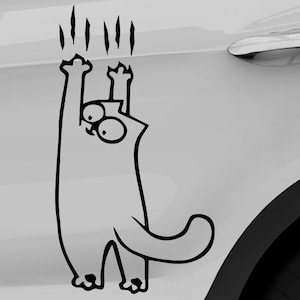 Pode incluir: Um adesivo de gato de desenho animado em preto e branco, projetado para parecer que está arranhando a porta de um carro. O gato tem olhos grandes e estica-se para cima com as patas, com marcas de garras acima.