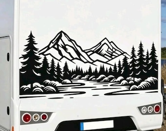 May include: A large black vinyl decal applied to the rear of a white recreational vehicle. The graphic features a stylized landscape illustration of jagged mountain peaks, a dense forest of pine trees, and a flowing river in a high-contrast design.