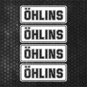 May include: Four white rectangular stickers with the word "ÖHLINS" in bold, black, block letters. The stickers are outlined in black and have a black background. The background is a dark gray, textured, hexagonal pattern.
