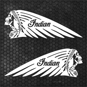 Könnte beinhalten: Zwei weiße Aufkleber mit dem Indian Motorcycle-Logo. Jeder Aufkleber hat ein stilisiertes indianisches Kopfschmuck- und Schädelprofil mit dem Wort "Indian" in einer Schreibschrift. Die Aufkleber sind vor einem schwarzen, strukturierten Hintergrund angeordnet.