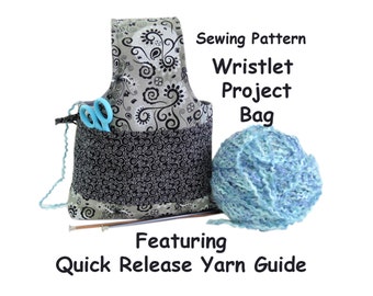 May include: A black and white floral fabric wristlet project bag with a quick release yarn guide. The bag has a zippered pocket and a handle. A ball of blue yarn and knitting needles are in the image. Sewing Pattern Wristlet Project Bag Featuring Quick Release Yarn Guide.