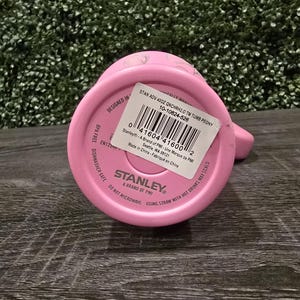 Puede incluir: Un vaso Stanley rosa, visto desde abajo, con una etiqueta blanca y el nombre de la marca. La etiqueta incluye informaci&oacute;n del producto y un c&oacute;digo de barras. El texto "BPA FREE" y "DISHWASHER SAFE" son visibles.