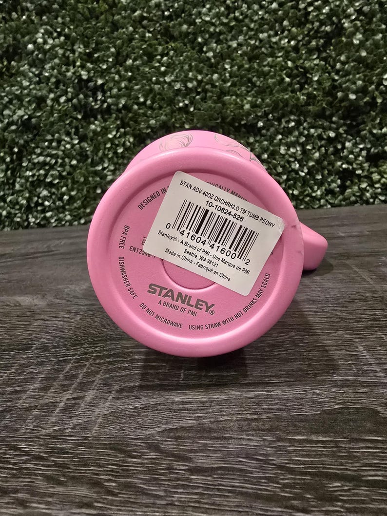 Puede incluir: Un vaso Stanley rosa, visto desde abajo, con una etiqueta blanca y el nombre de la marca. La etiqueta incluye informaci&oacute;n del producto y un c&oacute;digo de barras. El texto "BPA FREE" y "DISHWASHER SAFE" son visibles.