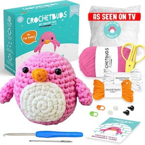 May include: A pink crocheted penguin DIY kit with a blue handle crochet hook, scissors, yarn, and a beginner's guide. The kit includes a box with the text "CROCHETBUDS DIY CROCHET KITS" and "Hi, I'm Polly!"