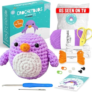 May include: A DIY crochet kit featuring a purple penguin with an orange beak and white belly. The kit includes yarn, a crochet hook, scissors, and a beginner's guide. The box reads "Crochetbuds DIY Crochet Kits" and "As Seen On TV."