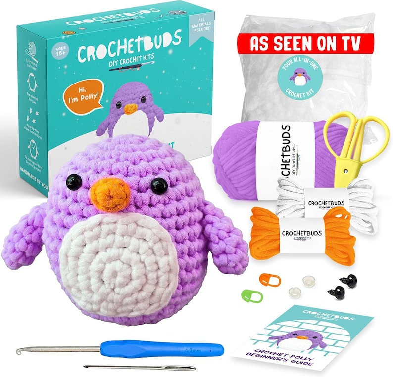 May include: A DIY crochet kit featuring a purple penguin with an orange beak and white belly. The kit includes yarn, a crochet hook, scissors, and a beginner's guide. The box reads "Crochetbuds DIY Crochet Kits" and "As Seen On TV."