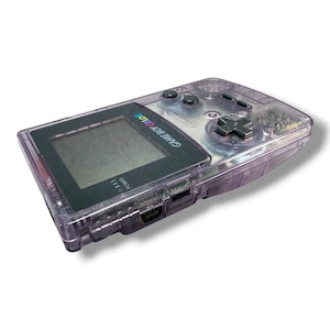 May include: A handheld Game Boy Color gaming console featuring a translucent purple plastic shell. The device includes a black screen bezel with the text GAME BOY COLOR, a directional pad, A and B buttons, and a power indicator light.