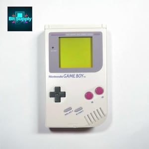 May include: A white Nintendo Game Boy handheld console with a green screen, gray accents, and pink buttons. The console features a directional pad, select and start buttons, and the text "Nintendo GAME BOY". The Bit Supply logo is in the upper left corner.