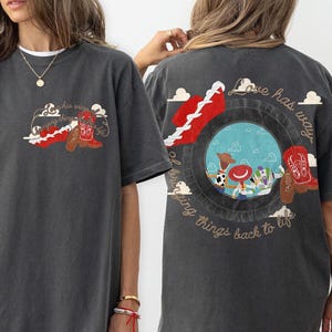 May include: A charcoal gray short-sleeve t-shirt featuring a small graphic on the front left chest and a large graphic on the back. Both graphics depict a red cowboy boot and the text Love has a way of bringing things back to life.