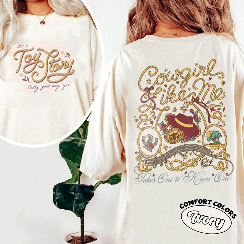 May include: An ivory t-shirt featuring a graphic on the back with the text Cowgirl Like Me, a cowboy hat, a horseshoe, and rope designs. The front shows the text Toy Story and Baby just say yes. The shirt is labeled as Comfort Colors Ivory.